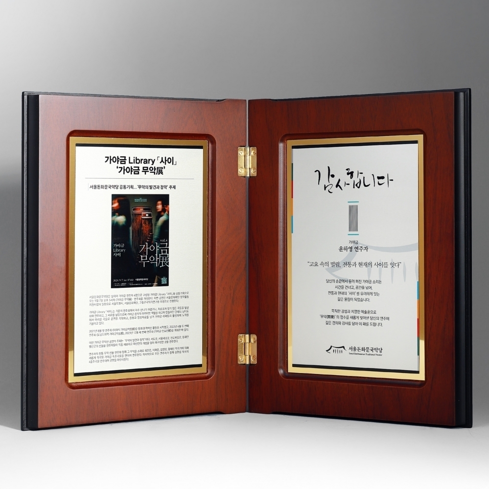 따뜻한 원목 텍스처와 황동 경첩이 조화를 이루는 양면 상패. 사진상패, 공로패, 감사패로 적합한 클래식한 액자형 구성입니다.