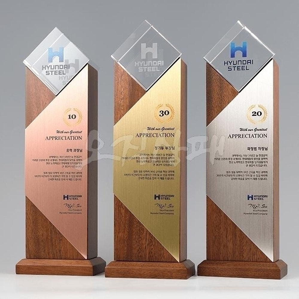 현대적인 감각의 FD1 0604 원목 시상식트로피. 영롱한 투명 크리스탈 헤드와 은은한 광택의 메탈판이 어우러져 장기근속 기념패나 기업 감사패 선물로 어울리는 중후하고 격식 있는 분위기를 연출합니다